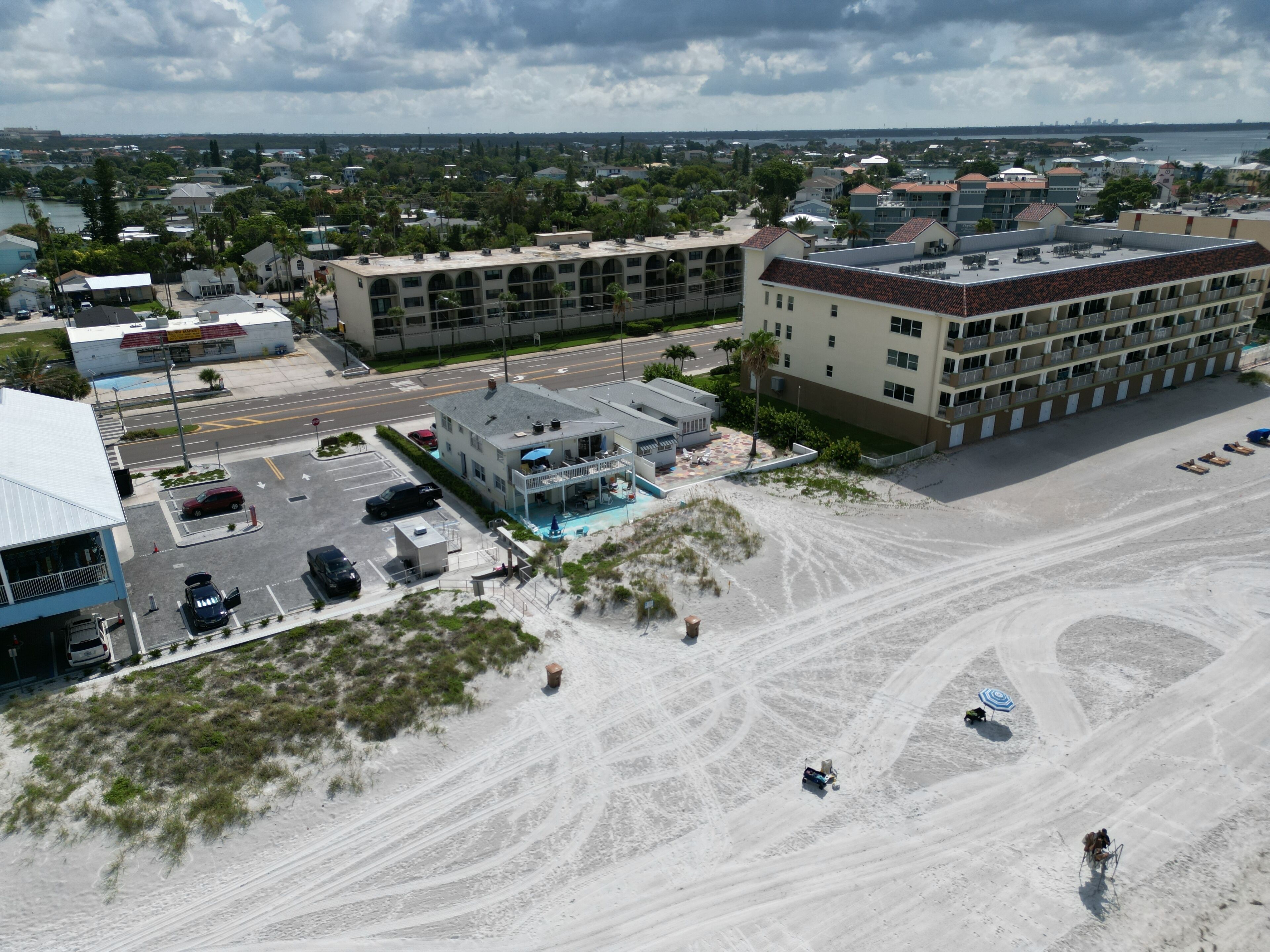 An aerial view of a coastal hotel with multiple buildings, a swimming pool, and a sandy beach area.