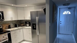 Une cuisine moderne avec des armoires blanches, un réfrigérateur en acier inoxydable, un four à micro-ondes et une cuisinière.