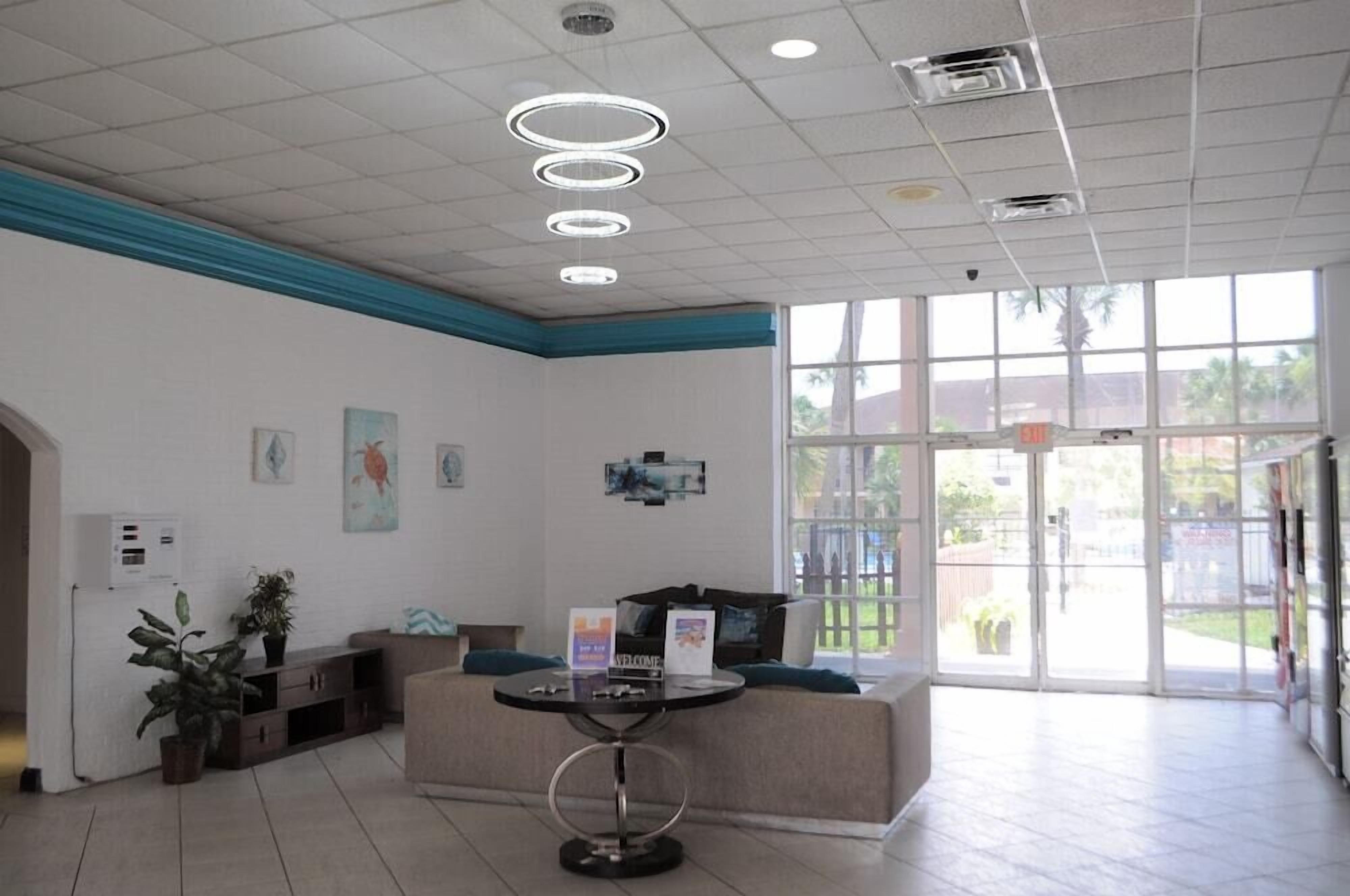 Un área de recepción con un sofá, una mesa redonda y un ventanal de vidrio que da al exterior.