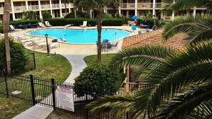 Un hotel amb una piscina envoltada de palmeres i seients de relax.