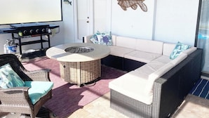 Une terrasse ensoleillée avec une table ronde, des meubles en osier et un ventilateur de plafond.