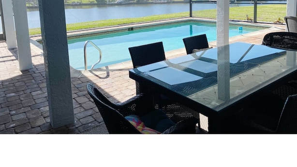 Un espace extérieur abrité comprenant une piscine, une table et des chaises.