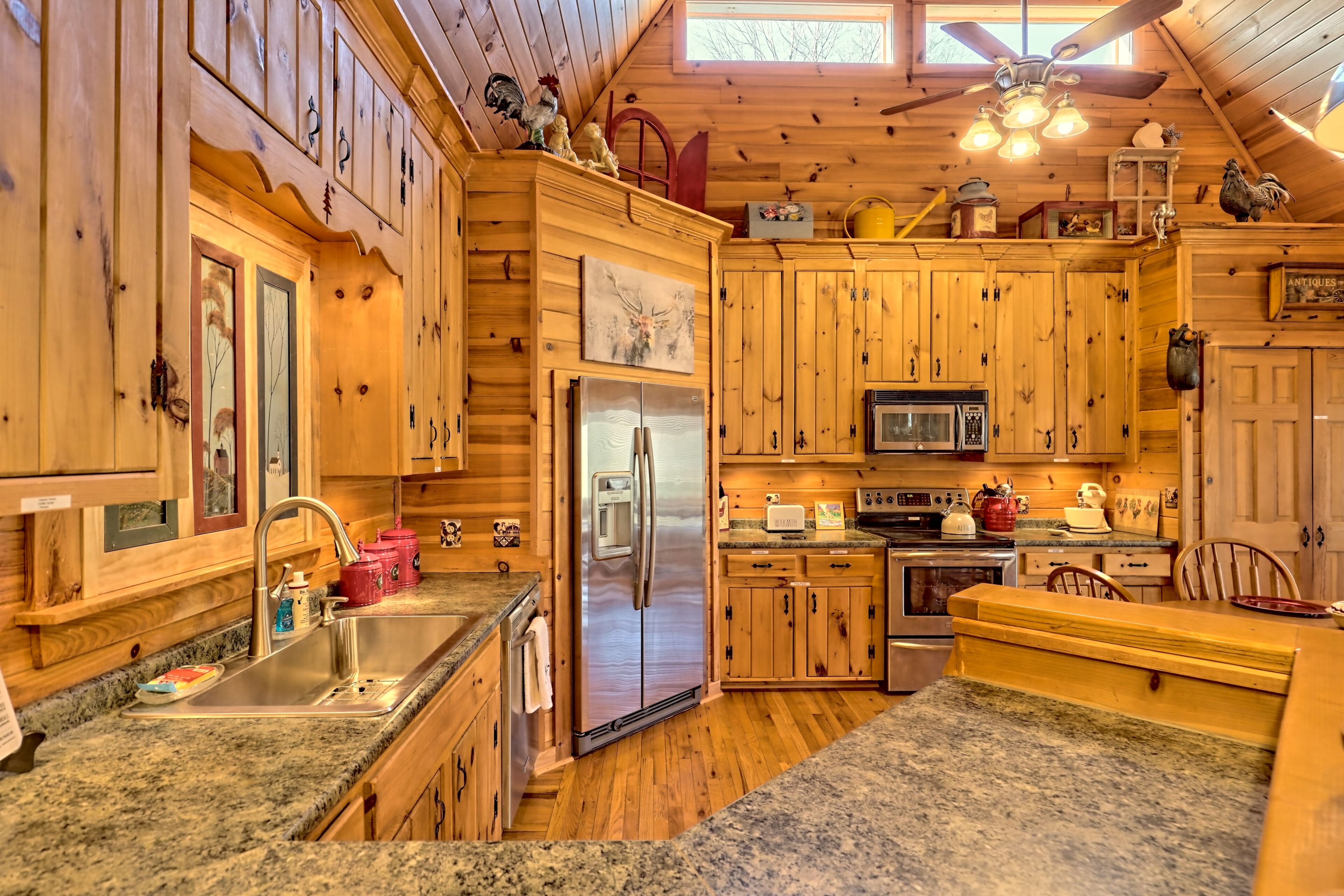 A wooden cabin-style kitchen with granite countertops, a stainless steel refrigerator, and a microwave.