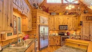 A wooden cabin-style kitchen with granite countertops, a stainless steel refrigerator, and a microwave.