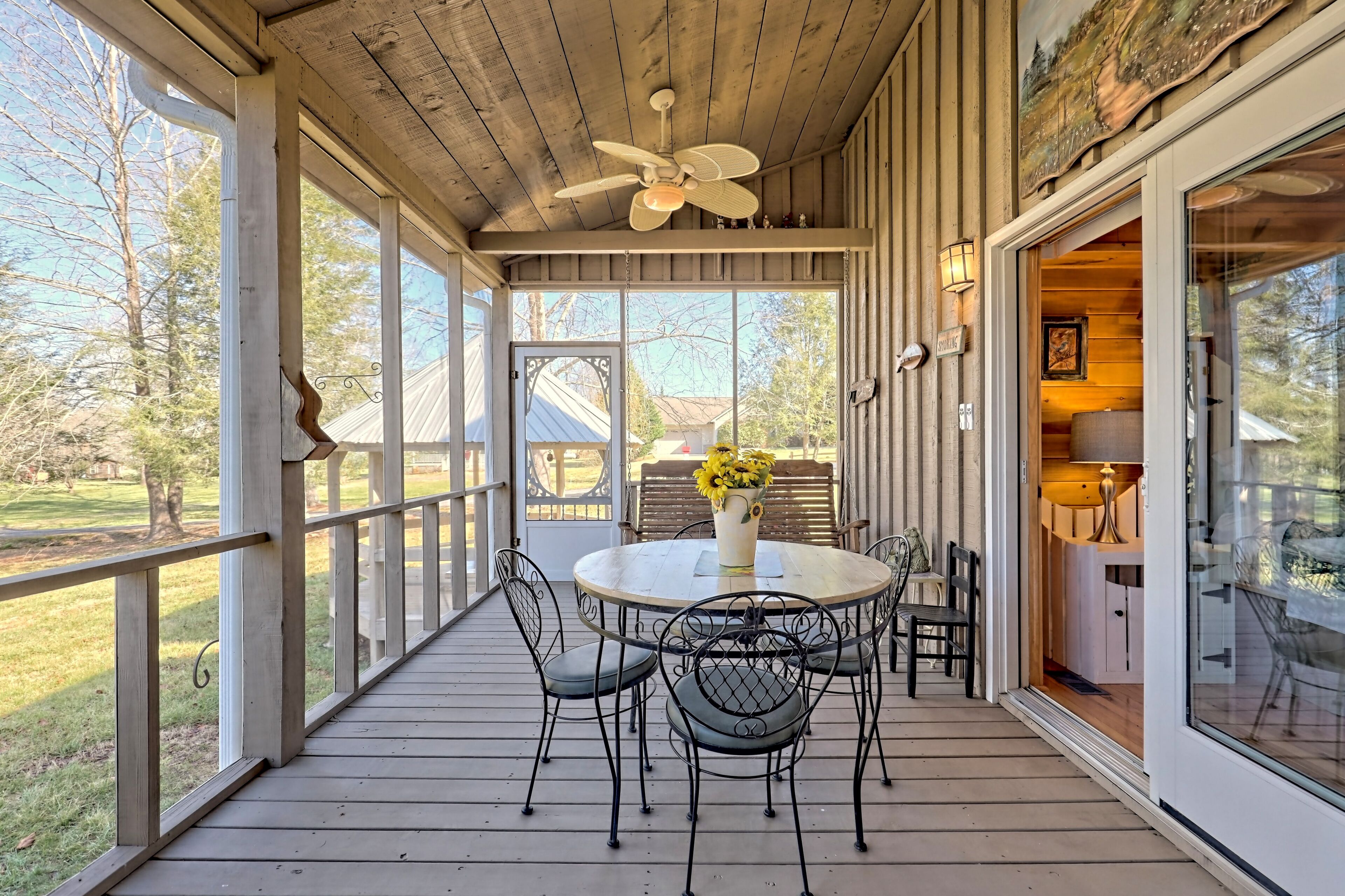 A covered outdoor patio with a round table, chairs, and a ceiling fan.