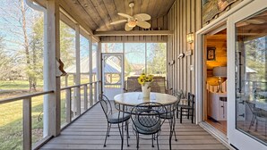 A covered outdoor patio with a round table, chairs, and a ceiling fan.