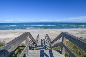 A wooden boardwalk leading to a beach with the ocean in the background. - The House of Shells (St. Augustine)