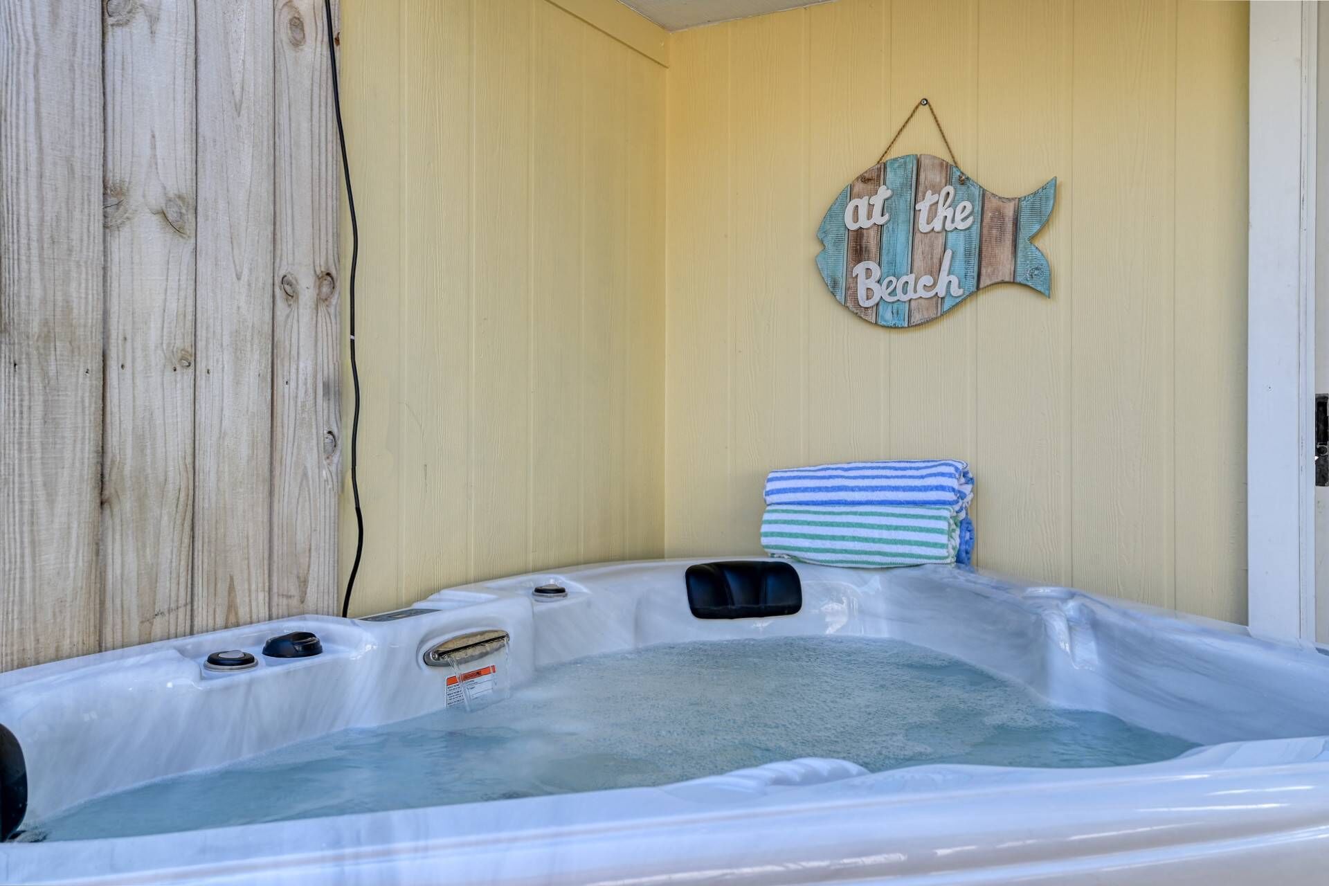 Ein Whirlpool mit Holzwand und einem Schild mit der Aufschrift 'at the Beach'.