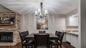 A dining room with a stone fireplace, a chandelier, and a painting on the wall. - Pools, Hiking & Lake, Ping Pong, Shuffleboard!    Close to SDC, Lake, Shows (Branson West)