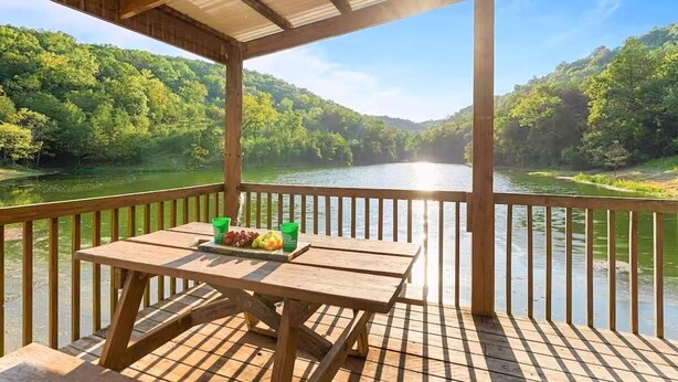 A wooden deck with a table and chairs overlooking a river and forested hills. - Pools, Hiking & Lake, Ping Pong, Shuffleboard!    Close to SDC, Lake, Shows (Branson West)