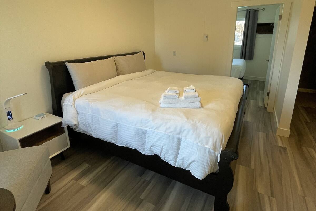 Una habitación de hotel con una cama, una mesita de noche y una lámpara.