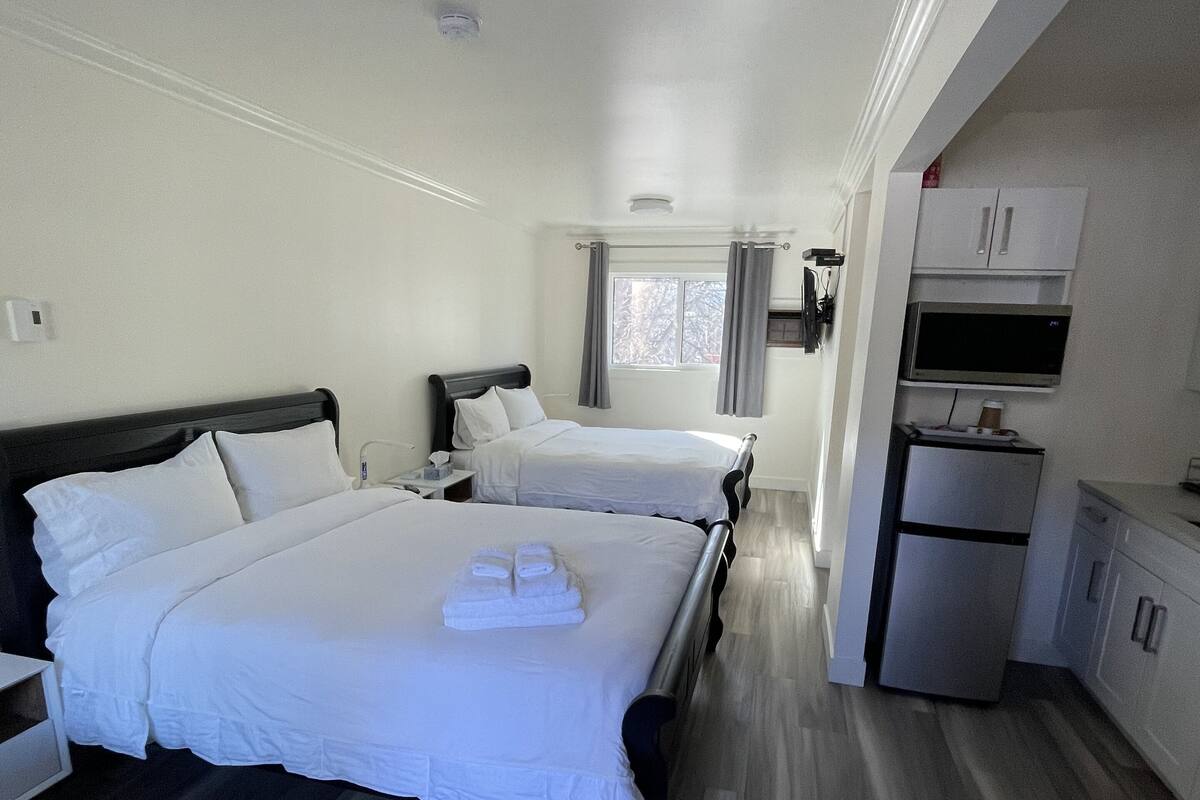 Habitación de hotel con dos camas, kitchenette y baño.