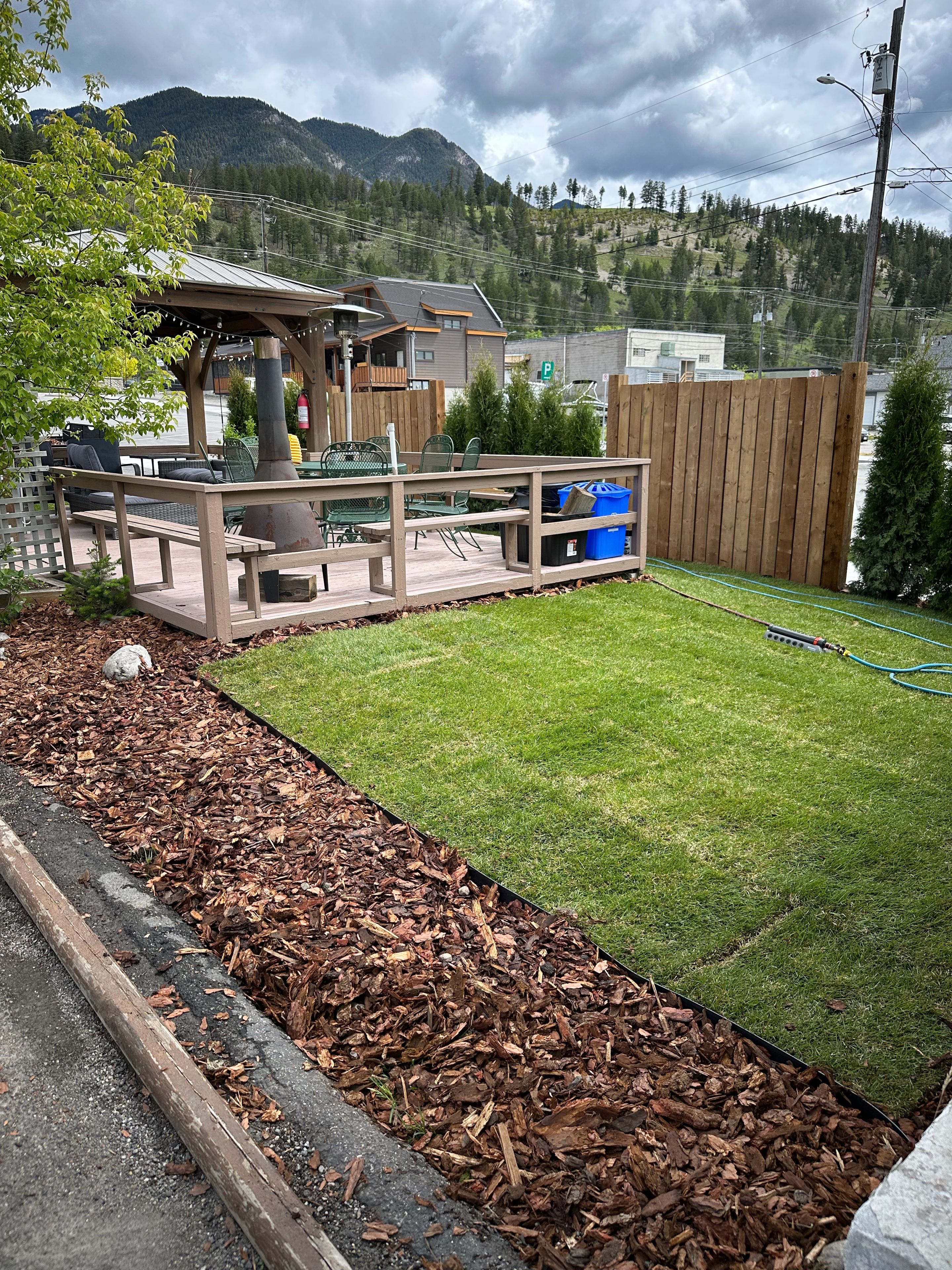 A backyard with a wooden deck, outdoor furniture, and a grassy lawn.