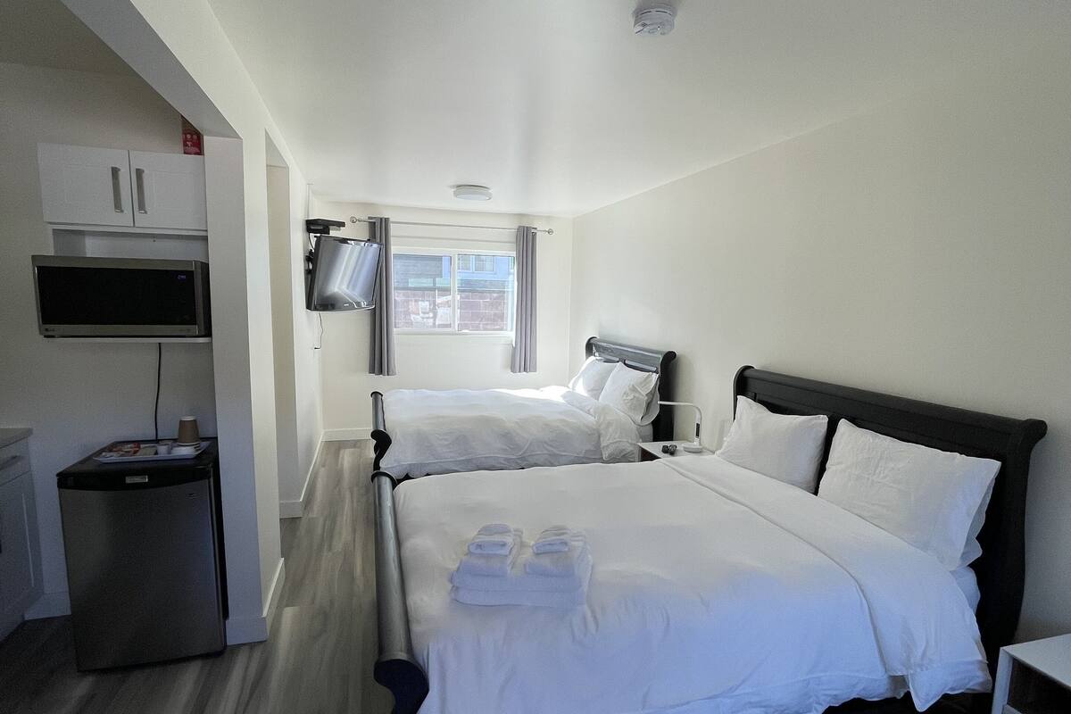 Una habitación de hotel con una cama, televisión, escritorio pequeño y microondas.