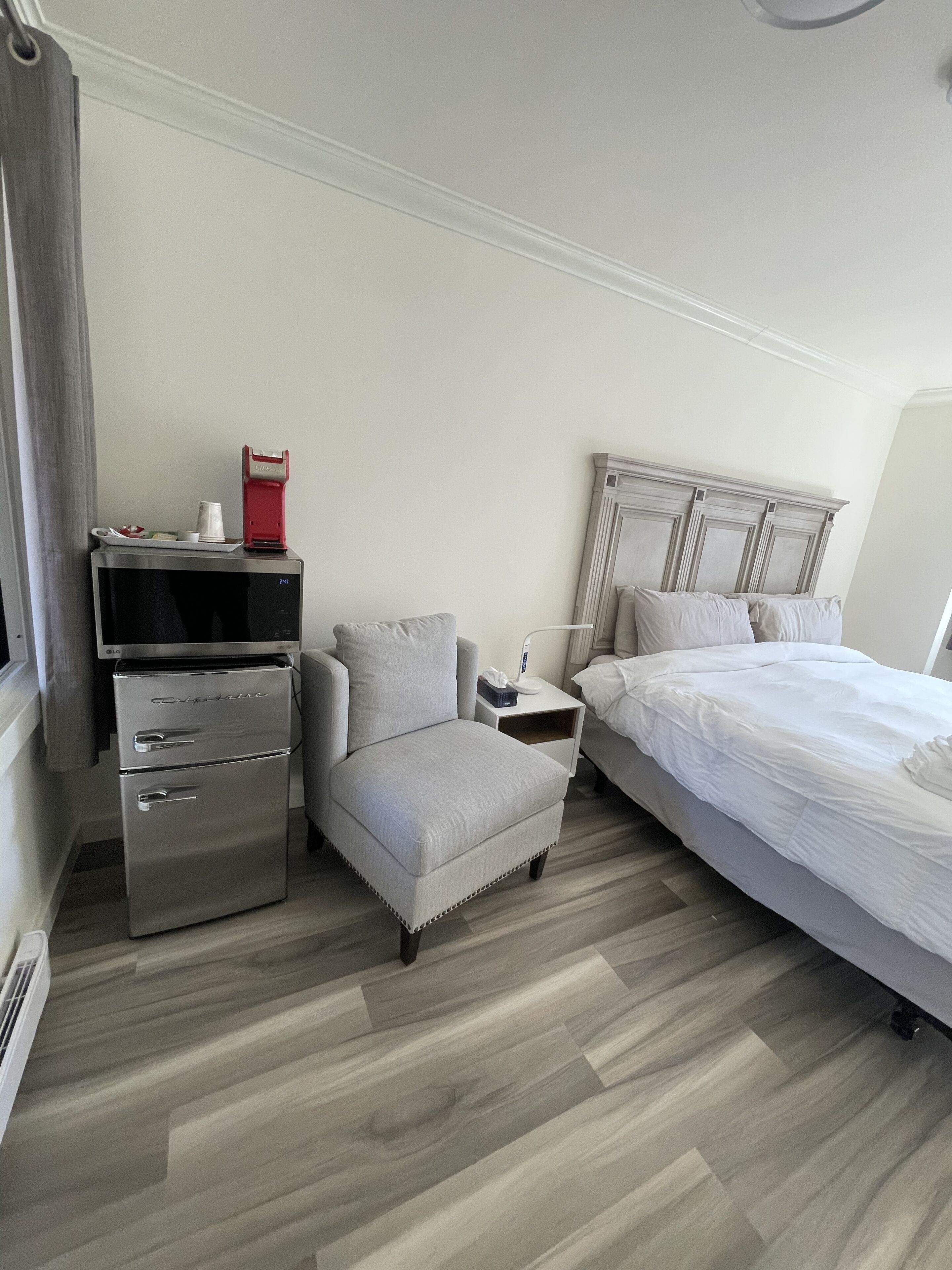 Une chambre d’hôtel équipée d’un lit, d’une chaise, d’une table de chevet, d’un réfrigérateur et d’un four à micro-ondes.