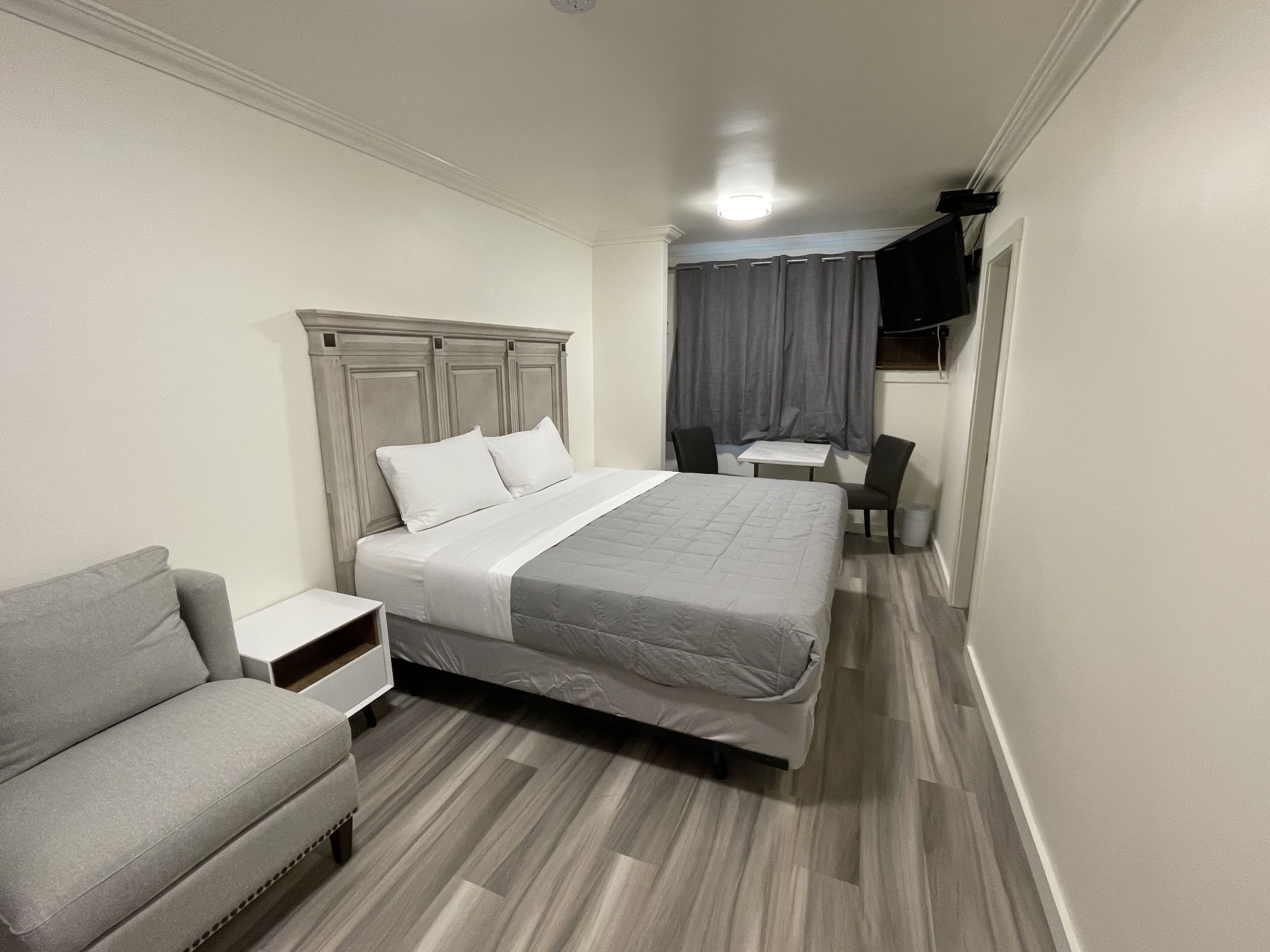 A hotel room with a bed, a sofa, a small table, and a TV.