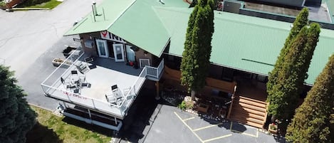 An aerial view of a building with a green roof, a covered patio with outdoor seating, and a parking lot.