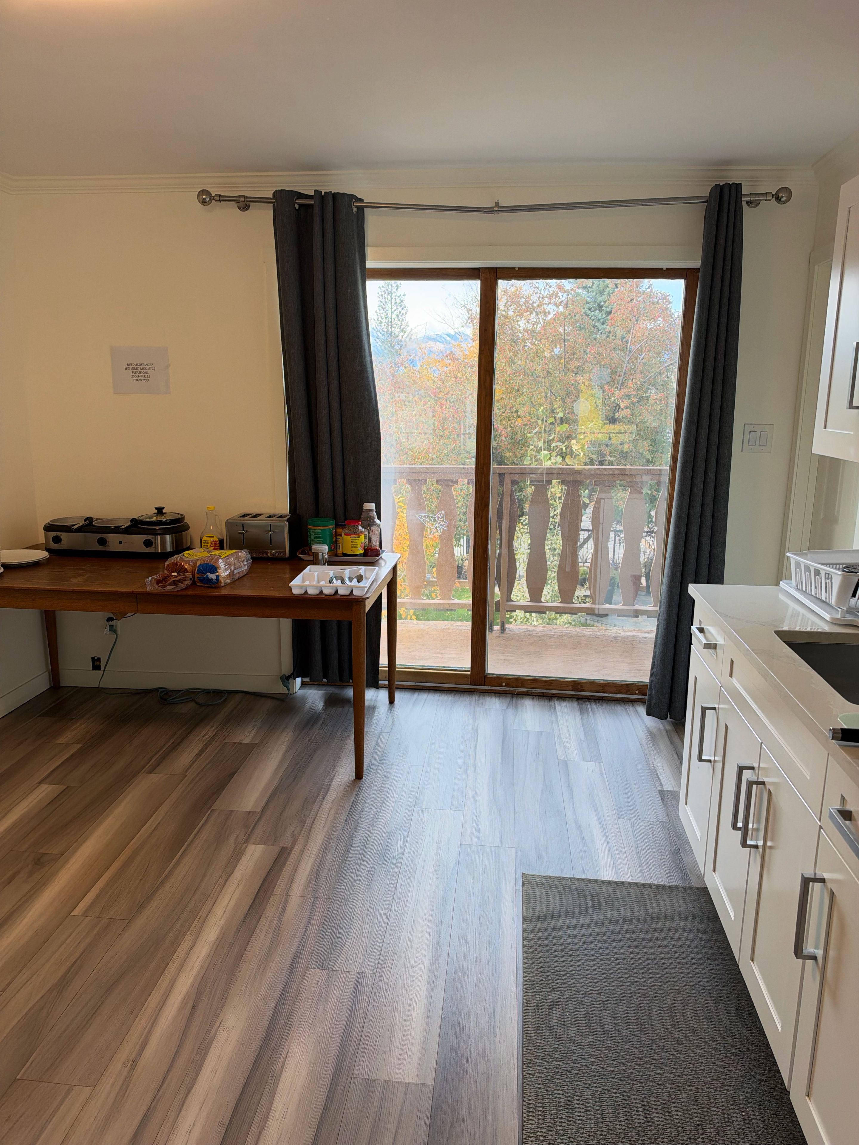 A kitchen with a dining table, a toaster, and a view of a balcony with a wooden railing.