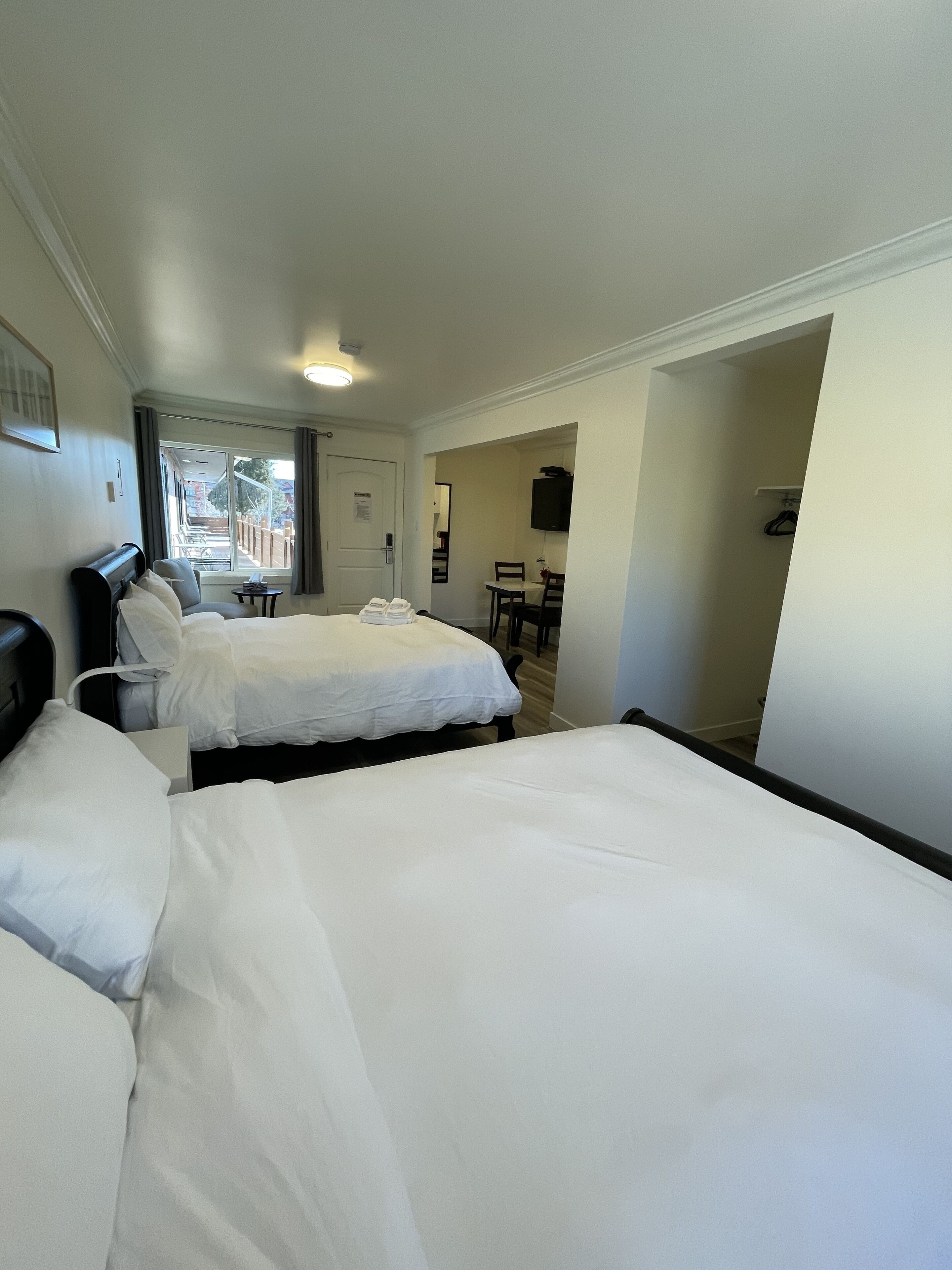 A hotel room with two beds, a small table, a chair, and a TV.