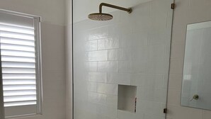 Un bany modern amb una banyera autònoma, una dutxa amb plat de pluja i un lavabo amb mirall.
