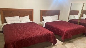 Twee eenpersoonsbedden met houten hoofdborden, wit beddengoed en een spiegel aan de muur.