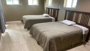 Een slaapkamer met twee bedden, een houten hoofdbord en een betegelde vloer.