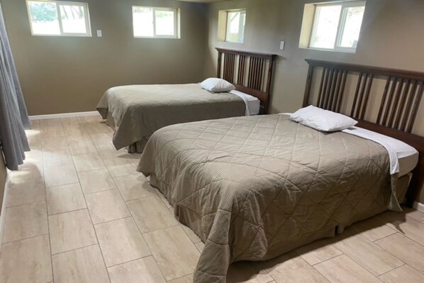 A bedroom with two beds, a wooden headboard, and a tiled floor. - Heart of Oakhurst Home (Oakhurst)