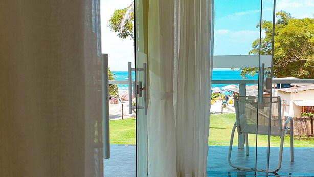Una habitación con puerta de cristal que da a un espacio exterior con vistas a la playa y al océano.