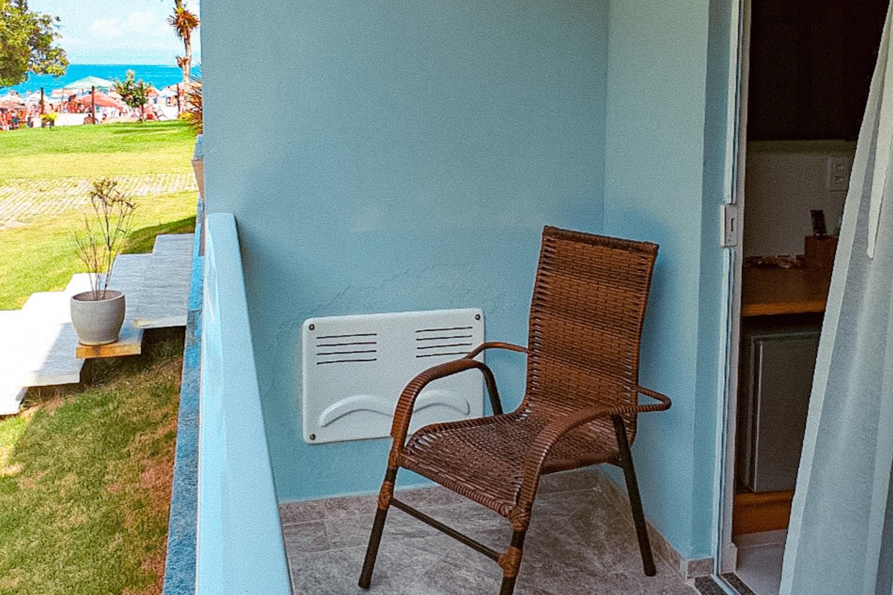 A wicker chair in a room with light blue walls, a small potted plant, and a white radiator.