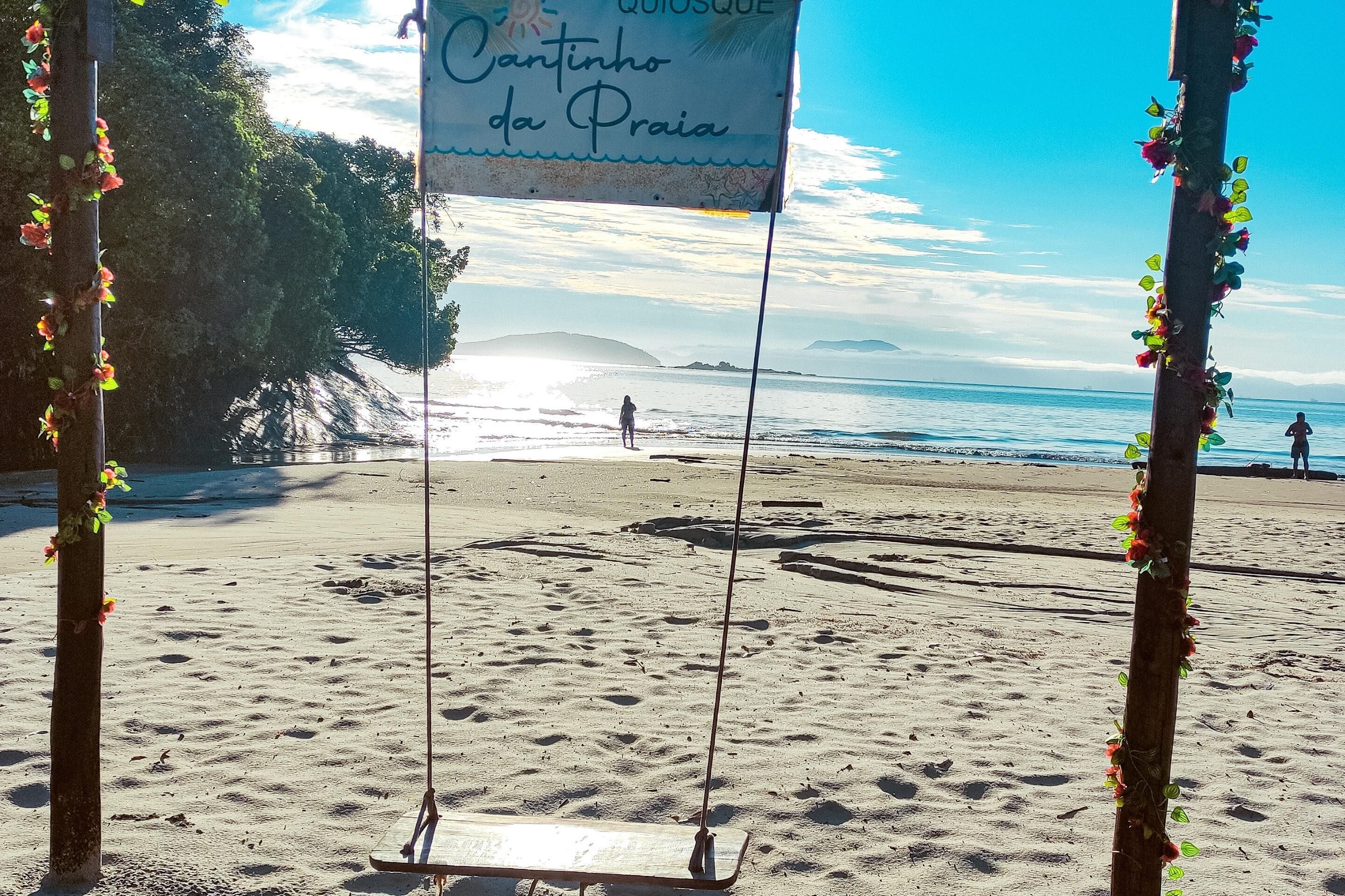 Una playa con un columpio y un letrero que dice "Cantinho da Praia".
