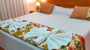Una cama bien hecha con ropa de cama floral, un cabecero de madera y una mesita de noche con una lámpara.