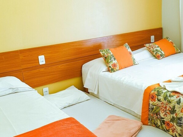A hotel room with two beds, each with white bedding and orange accents.