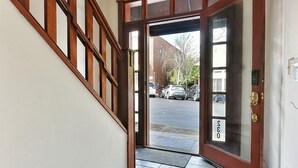 A hallway with a wooden staircase and a door leading outside. - 230 4th Street (Ashland)