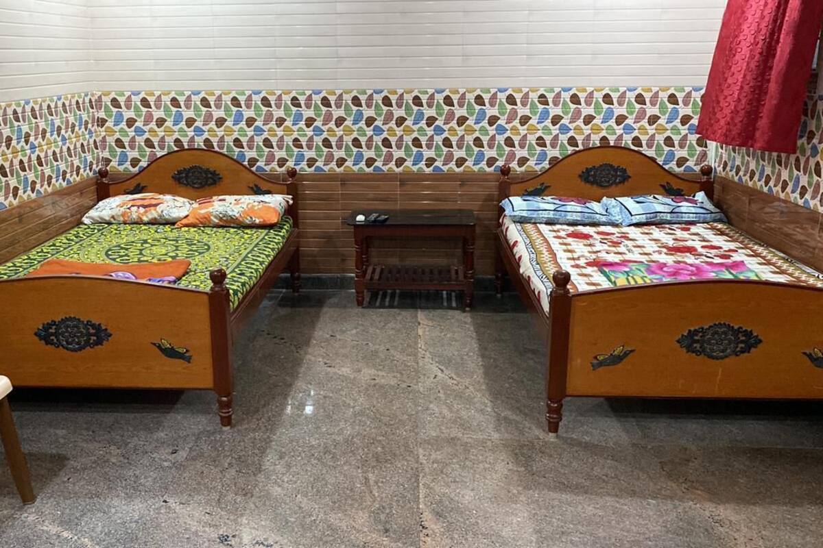 A room with two wooden beds, a small table, and a bench.