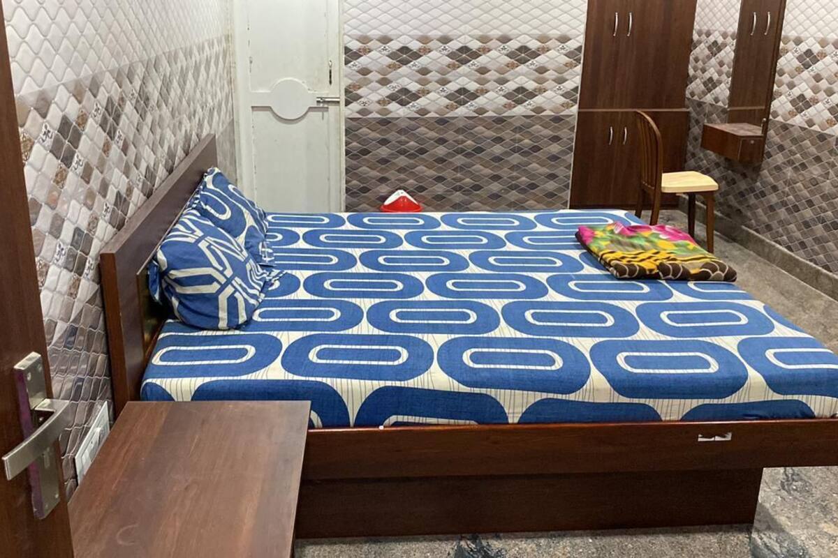 A bed with a patterned bedspread, a wooden headboard, and a bedside table with a lamp.