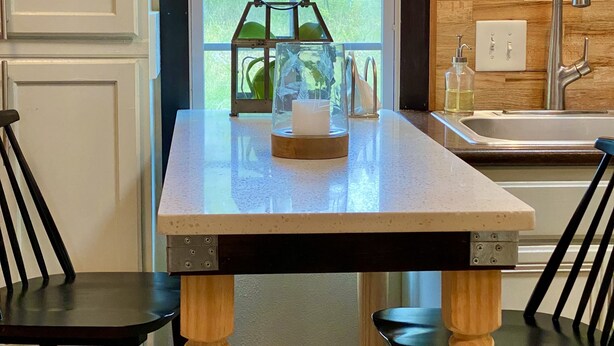 Una cocina con pared de madera, una ventana, un lavamanos y una mesa con sillas.