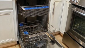 Una cocina con lavavajillas, horno y un cartel que dice 'CLEAN'.
