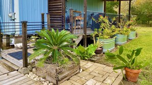 Un edificio de metal azul con una terraza de madera, plantas en macetas y un letrero con el número 809.