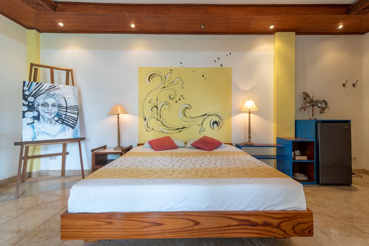 Une chambre à coucher avec un lit en bois, deux lampes de chevet, une grande peinture abstraite au mur et une petite statue sur la table de chevet.
