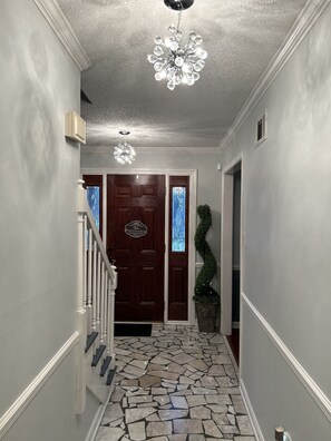 Hall view of foyer with warm tones and updated light fixtures 