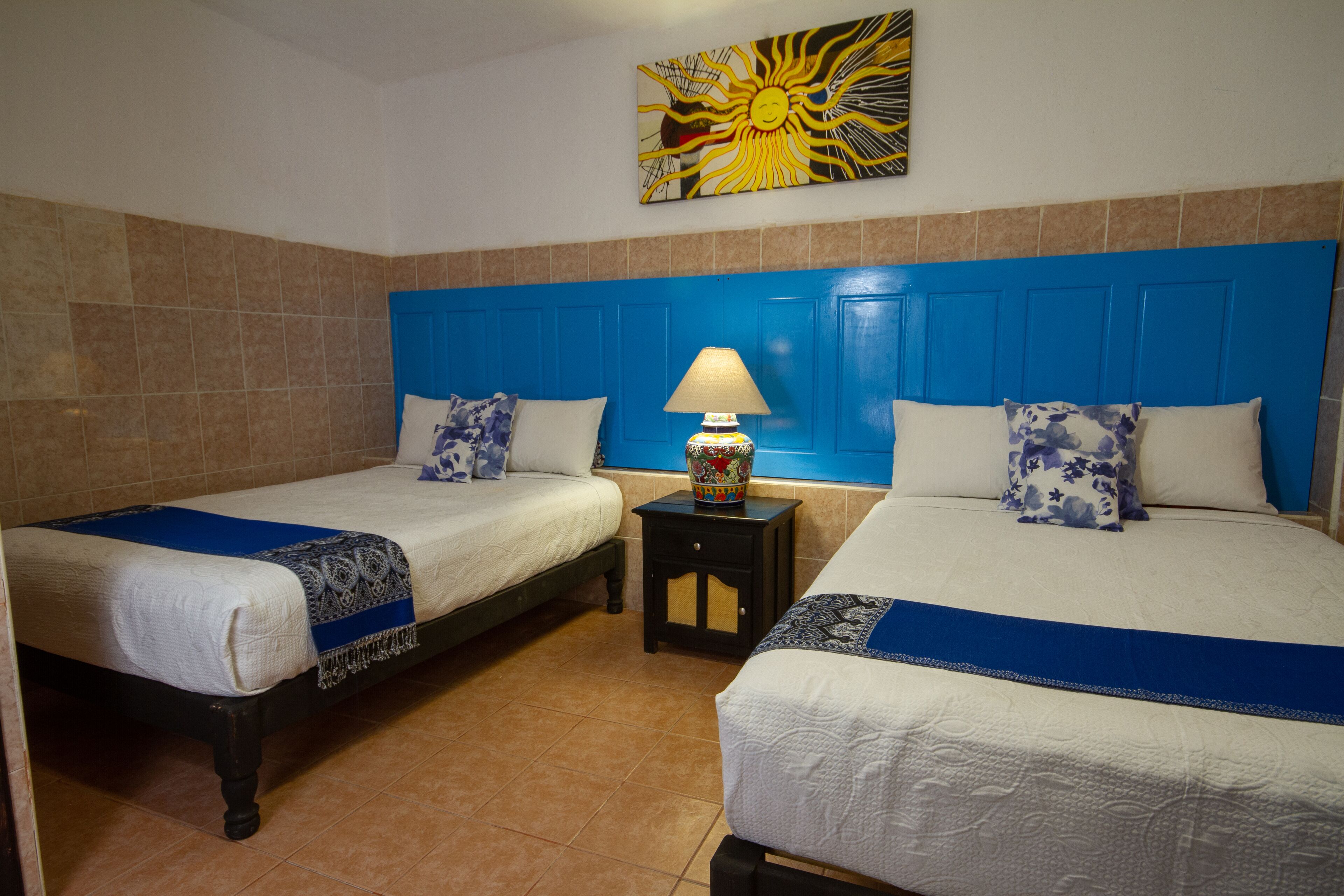 A hotel room with two beds, a nightstand, and a wall painting.
