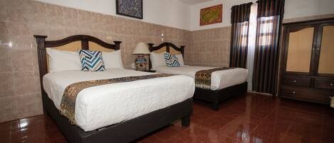 A hotel room with two beds, a ceiling fan, and a wardrobe.