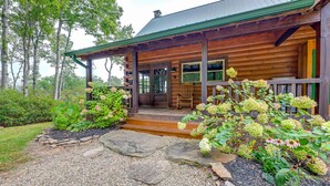 A rustic log cabin with a porch, stone pathway, and lush garden. - Mtn Views, Yard, & Fire Pit: Multi-Level Cabin (Franklin)