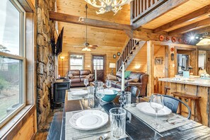Cozy cabin-style room with a dining table, exposed beams, and a comfortable seating area.