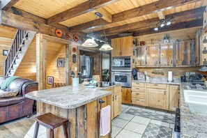 Cozy cabin-style home features a kitchen with wooden cabinets, a large island, and modern appliances, plus a comfortable living area with a leather couch.