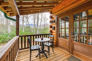 Enjoy dining or socializing on the deck with a round table and two chairs, surrounded by a view of the surrounding landscape.
