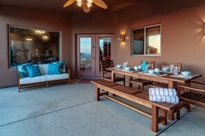 Enjoy dining al fresco in this scenic outdoor space with a wooden table, matching benches, and a comfortable sofa.