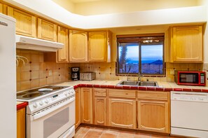 Enjoy a view of the outdoors from this kitchen with a stove, oven, microwave, and dishwasher.