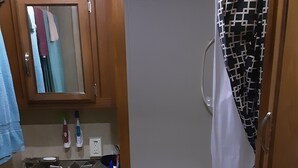 Een badkamer met een wastafel, spiegel en douchegordijn.