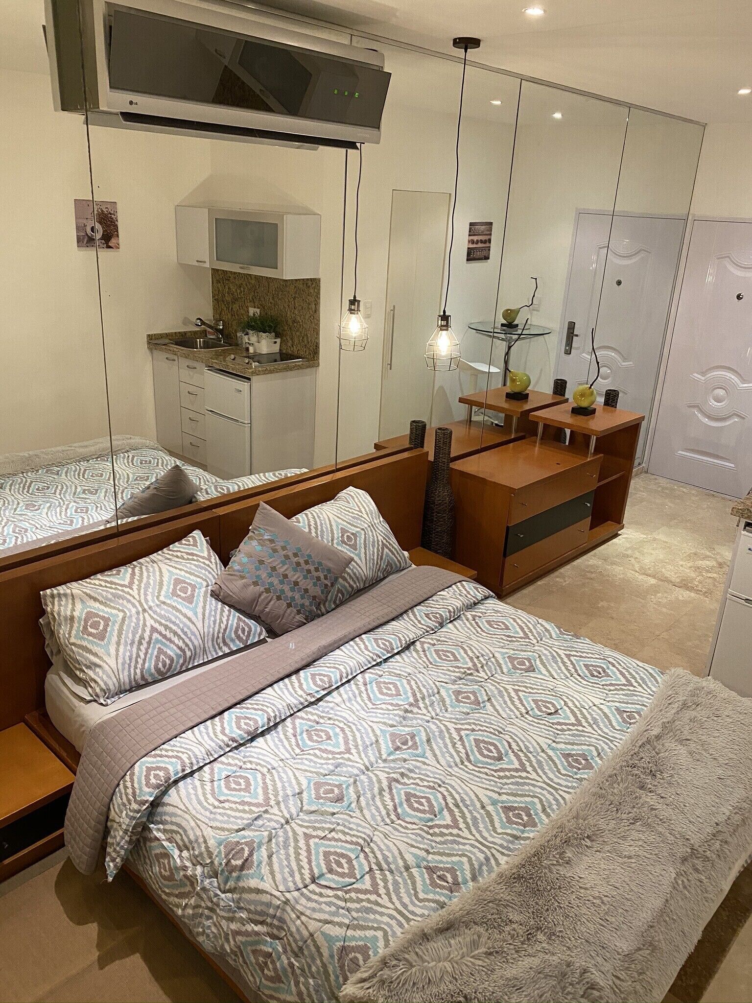 Une chambre à coucher moderne comprenant un lit, des tables de chevet, une commode, une coiffeuse et un grand miroir.